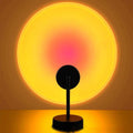 LED sunset projection lamp creating warm yellow and pink sunset light on wall with black base and adjustable stand