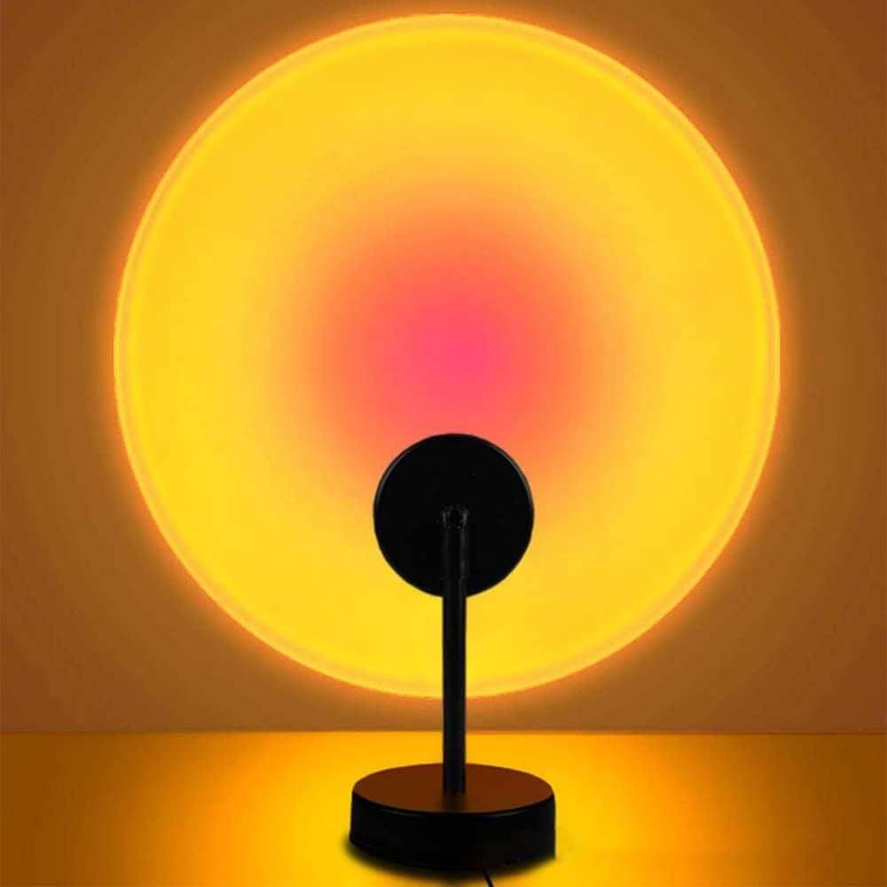 LED sunset projection lamp creating warm yellow and pink sunset light on wall with black base and adjustable stand